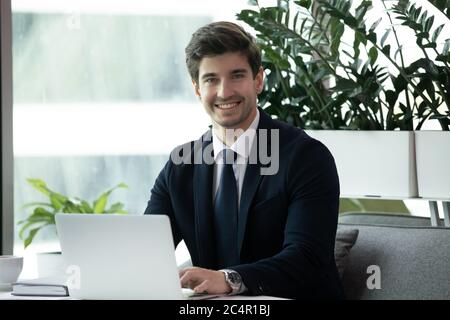 Happy businessman in formal wear using laptop and smiling Stock Photo
