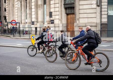 London cycling as teenagers with bikes riding casual careless and unprotected with no helmets on King William Street on Sunday morning, London, UK Stock Photo