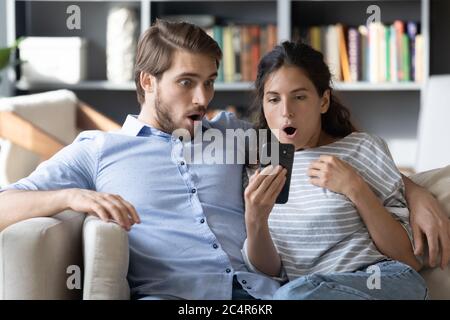 Shocked young man and woman looking at phone screen Stock Photo