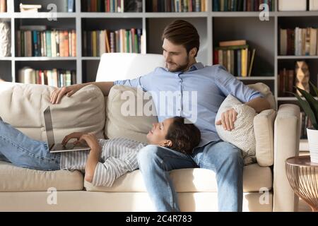 Satisfied young woman using laptop, lying on man laps Stock Photo