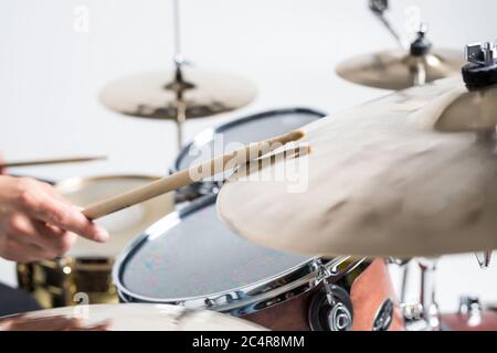 Close up of hands of male drummer holdning drumsticks sitting and playing drums in studio Stock Photo