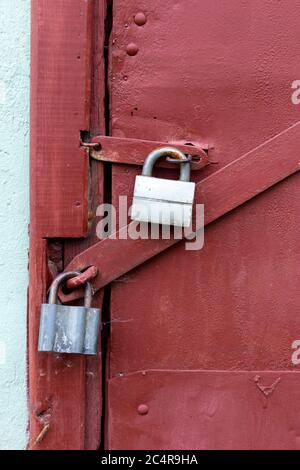 Two gray locks on a burgundy door. Perfect protection. Stock Photo