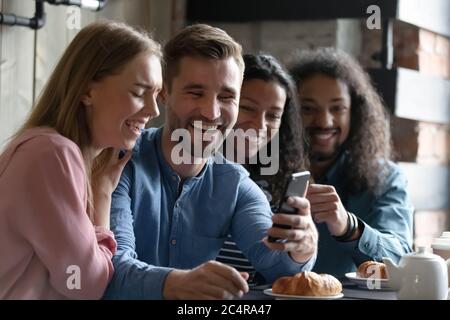 Friends having fun use smartphone watching video in cafe Stock Photo