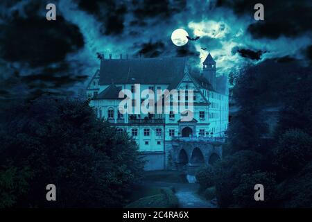 Haunted house at night. Old spooky castle in full moon. Creepy view of dark mystery mansion with bats. Scary gloomy scene for Halloween theme. Horror Stock Photo