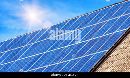 Solar panel on residential house rooftop. Many blue solar cells on building top for alternative energy. Photovoltaic eco panels on home roof. Technolo Stock Photo