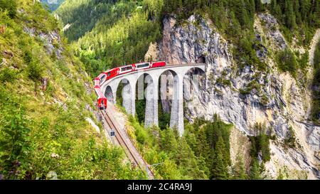 Landwasser Viaduct in Filisur, Switzerland. It is landmark of Swiss Alps. Red train of Bernina Express on high bridge in mountains. Panoramic view of Stock Photo