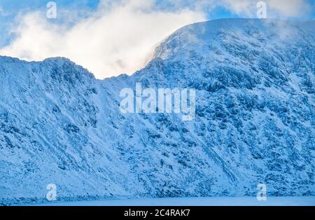 Striding Edge and Helvellyn in Winter snow above frozen Red Tarn, English Lake District, Cumbria, England, UK Stock Photo