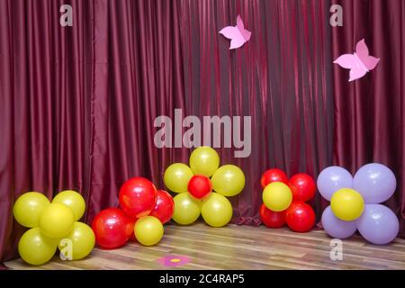 Red curtain . Flower made from balloons isolated on Red curtain background. Red, white, yellow flower balloon. Stock Photo