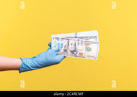 Profile side view closeup of human hand in blue surgical gloves holding and showing fan of american dollar money in hand. indoor, studio shot, isolate Stock Photo