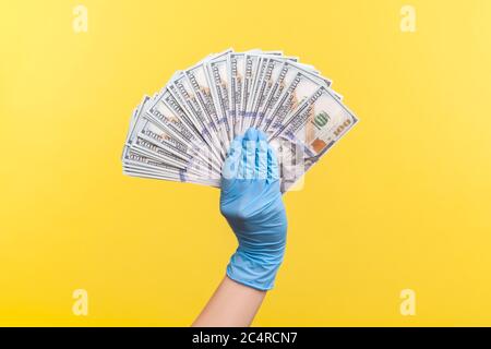 Profile side view closeup of human hand in blue surgical gloves holding and showing fan of american dollar money in hand. indoor, studio shot, isolate Stock Photo