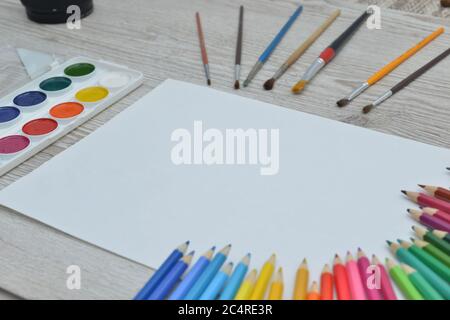 Tools for drawing, stationery, artist's workplace. Paint and pencils and clear paper on wooden table, top view, flat lay, copy space. school drawing Stock Photo