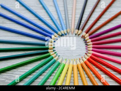 colored wooden pencils are arranged in a circle. A circular palette of colored pencils. Close-up, on wooden background Stock Photo