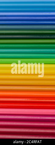Colored wooden pencils are arranged in a row. A palette of colored pencils. Close-up, on wooden background Stock Photo