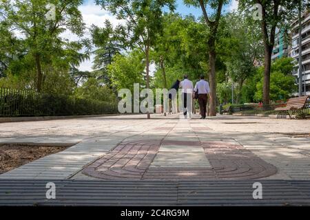 Madrid, Spain - May 25, 2018: Two businessmen walking down  a tree shaded sidewalk in the centre of the city Stock Photo