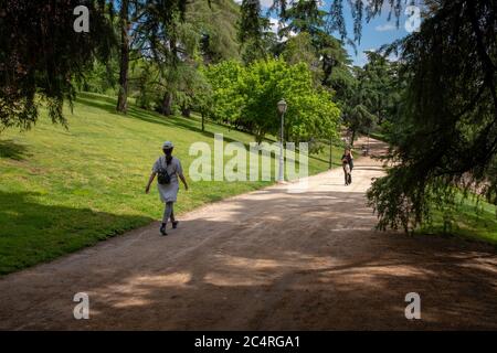 Madrid, Spain - May 25, 2018: Two young women walking down  a park alley in the centre of the city Stock Photo