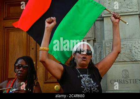 Protesters from the 'Africans in the diaspora assemble outside Christie's in London to demand the return of 'looted' African artefacts. Stock Photo