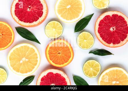 Various sliced citrus fruits: lime, orange, red and yellow grapefruit with green leaves on a white background, texture. Stock Photo