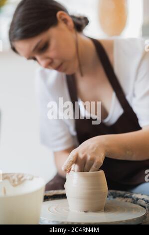 Close-up of potter making pot in pottery workshop. Using sponge and water for moisturizing clay. Stock Photo