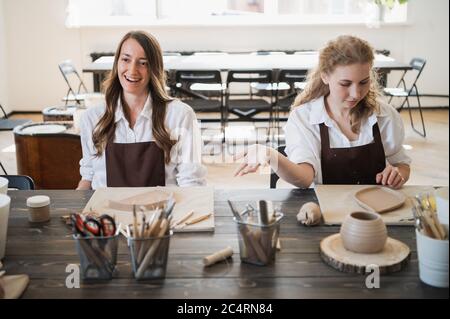Women working In pottery studio, smiling and talking. Ceramic workshop, pottery master class. Stock Photo