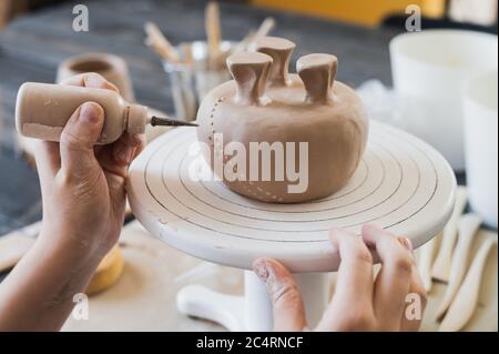 Child in the process of decorating the clay vase. Children pottery studio. Stock Photo