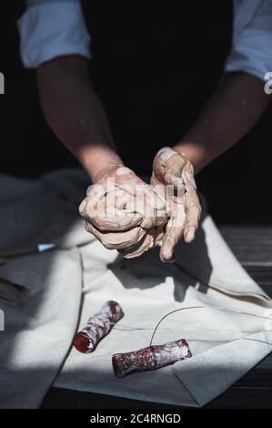Clay ball. Close-up of female hands knead a ball made of clay to start working on the wheel. Stock Photo