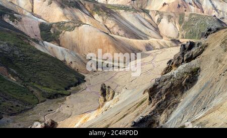 Pink creek is flowing down Iceland's mossy highlands on a sunny day Stock Photo