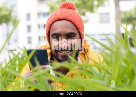 young man  with smart phone and yellow jacket and red cap Stock Photo