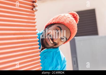 face of a  young man behind a wall with red cap Stock Photo