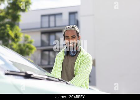 young man in front of a car with headphones Stock Photo
