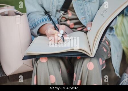 Sketchbook with a drawing of a house close-up. Girl draws in the fresh air. Front view Stock Photo
