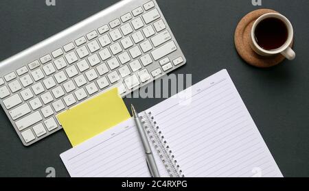 Top view of office table with wireless keyboard, coffee, notepad and pen. Stock Photo