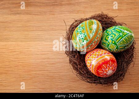Easter holiday and spring celebration concept with three easter eggs decorated with a complex pattern in a birds nest isolated on a wood background wi Stock Photo