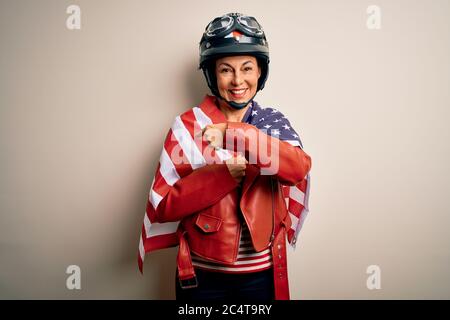 Middle age motorcyclist woman wearing motorcycle helmet and united states flag very happy pointing with hand and finger Stock Photo