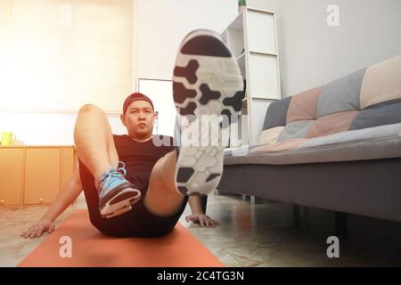 Asian male doing exercise at home to stay healthy on new normal lifestyle, indoor home workout concept, core abs abdominals training Stock Photo