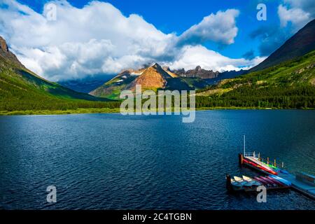 2635 Canoes sit wating at Swiftcurrent Lake during sunrise with Mount Gould in the distance Stock Photo