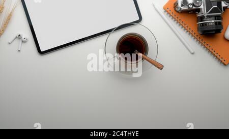 Top view of modern worktable with blank screen tablet, tea cup, camera, stationery and copy space Stock Photo