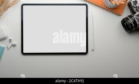 Top view of modern worktable with blank screen tablet, tea cup, camera, stationery and wireless earphone Stock Photo