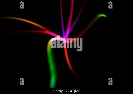 Glowing neon lines on a black background. Multicolor star shaped defocused lines. Blurred abstract background. Stock Photo