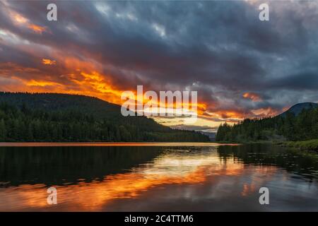 Amazing orange sunset over lake with reflection at Inland Lake Provincial Park on the sunshine coast near Powell River on Inland Lake Provincial park. Stock Photo