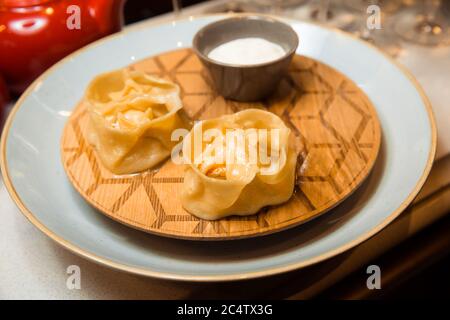 Juicy manti on a white plate. Served with sauce. Traditional dish. Stock Photo