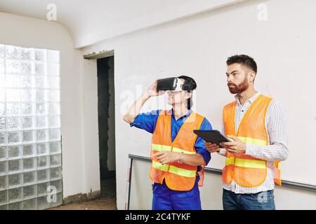 Contractor and builder using application for virtual reality headset to check wiring and pipes in house walls Stock Photo