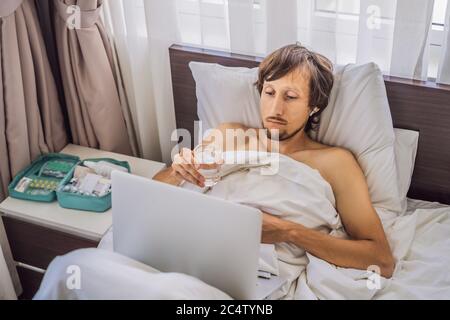 Male patient is sick while lying in his bed and calls an online doctor through a gadget Stock Photo