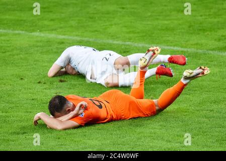 Two injured football players lays on the grass after collision. Stock Photo