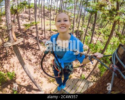 Young attractive woman in adventure rope park in safety equipment Stock Photo