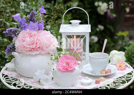 romantic decoration in white with tea cans, peonies and lantern Stock Photo