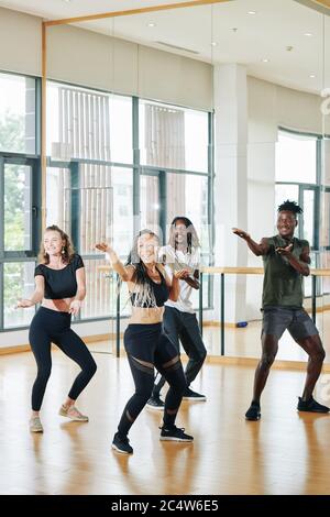 Excited happy group of young dancers training in studio in front of mirror Stock Photo