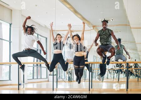Multi-ethnic group of happy dancers jumping from excitement after productive training Stock Photo