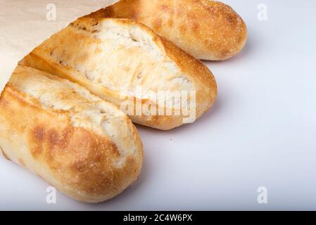 French bread rolls in the paper bag isolated on light background. Stock Photo