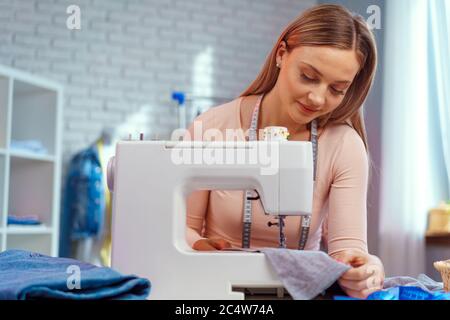 Young seamstress working on her sewing machine on textile factory Stock Photo
