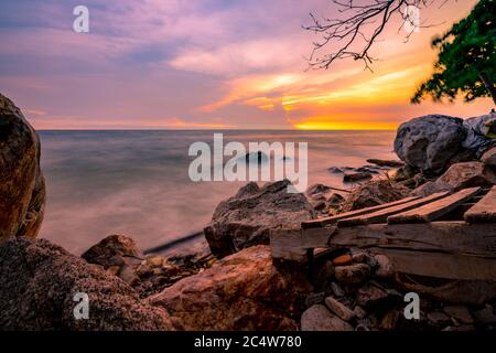 Rock beach with blue and golden sunset sky. Skyline between sea water and sky in the evening. Calm ocean with soft wave. Summer travel at tropical sea Stock Photo